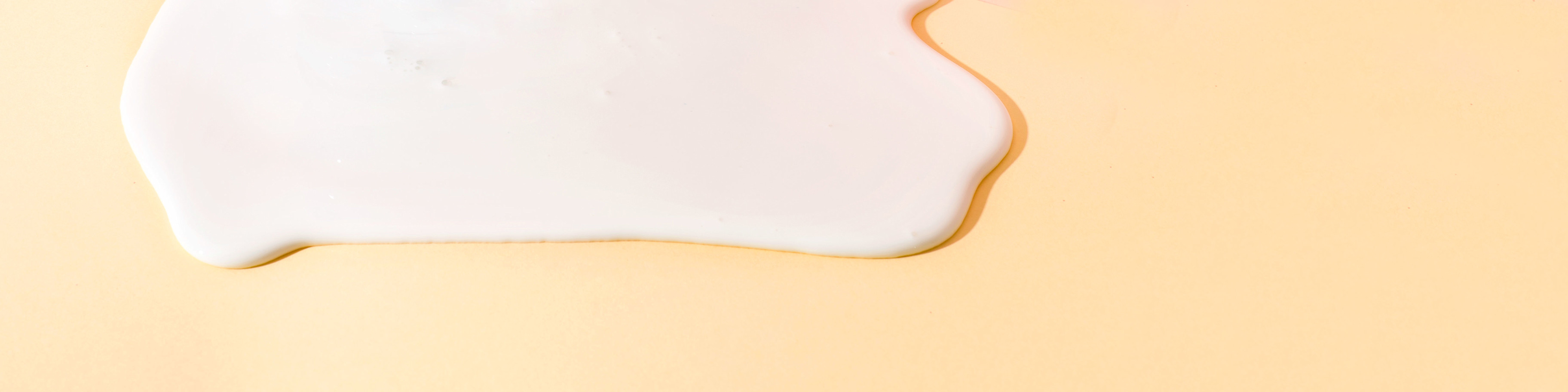 Closeup of calcium as a white liquid on a peach-colored background.