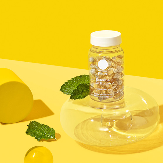 Bottle of Essential for Women 18+ vitamins against a yellow backdrop